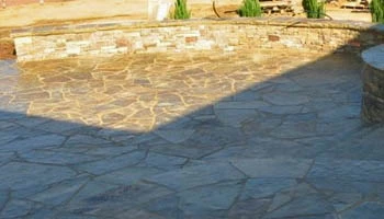 Custom stone patio with seating wall created by Ambiance Landscape in Brandon, MS.